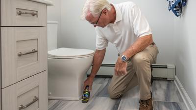 An inspector checking a bathroom for moisture damage with a handheld meter.